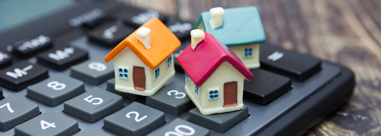 Hypotheek; drie kleine huisjes staan op een rekenmachine